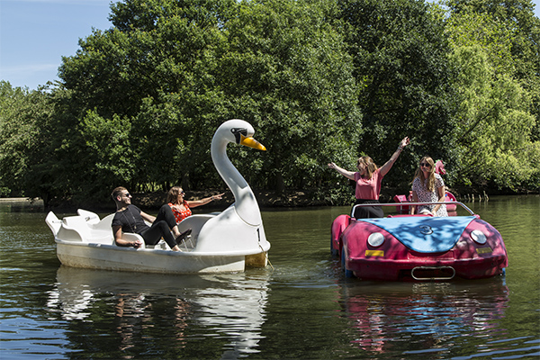 Group of people on two pedlows, one is a swan and one is a car.