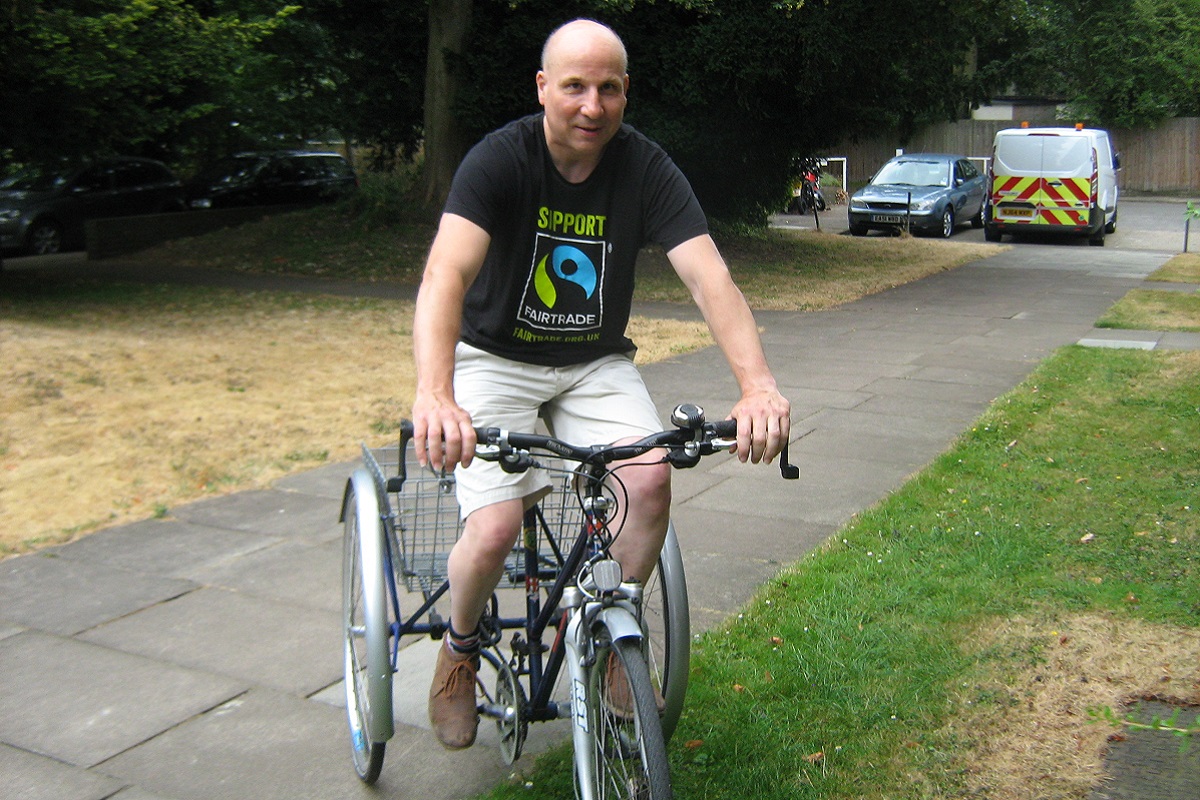 Photo of Neil riding his accessible cycle on a path.