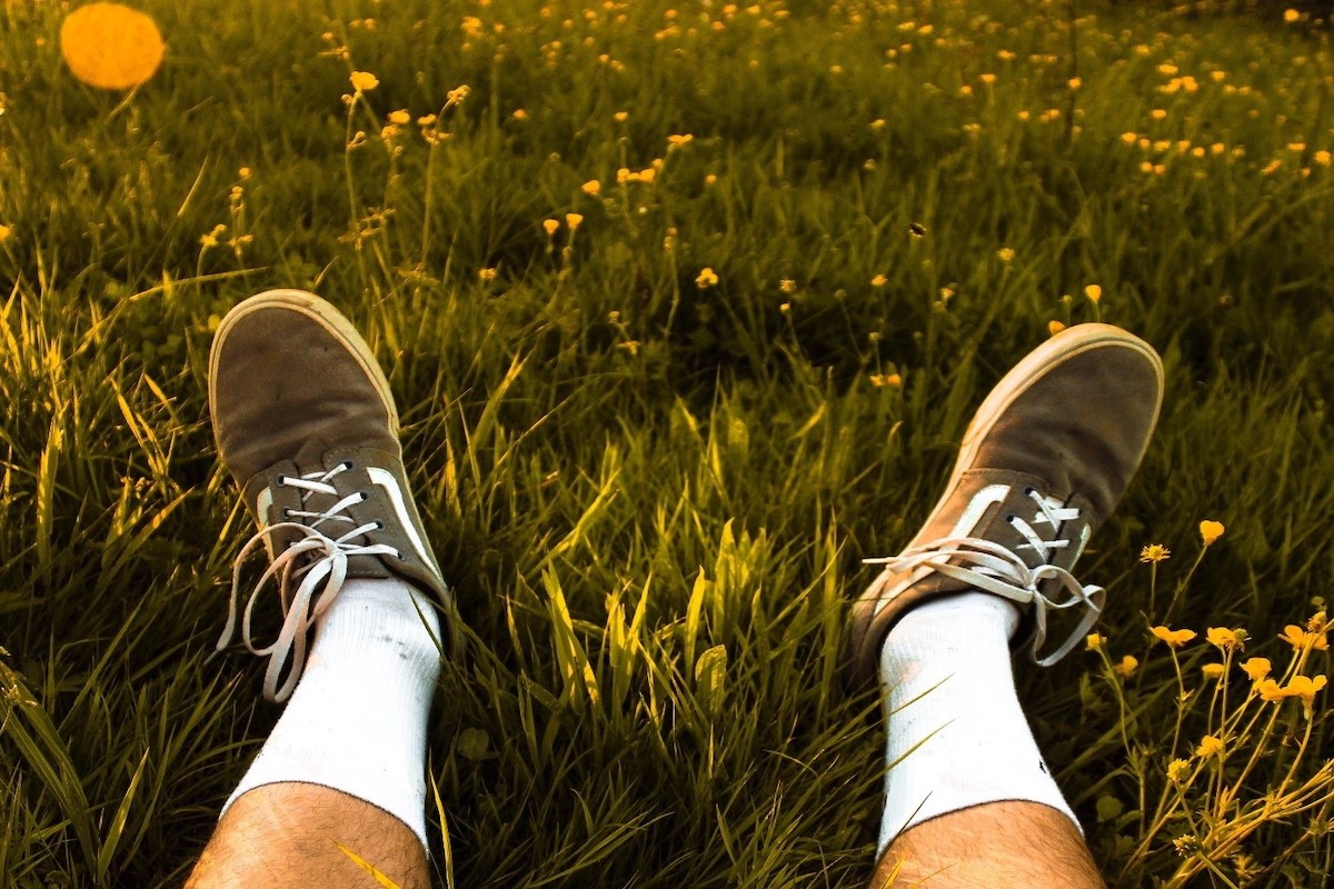A person lying in the grass on a Summer's day with walking shoes on