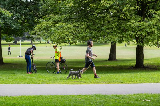 Cyclists and a man walking a dog in Southwark Park