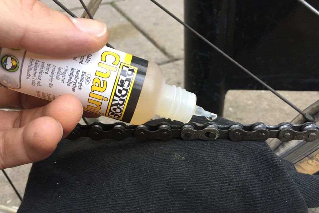 person oiling a bike chain